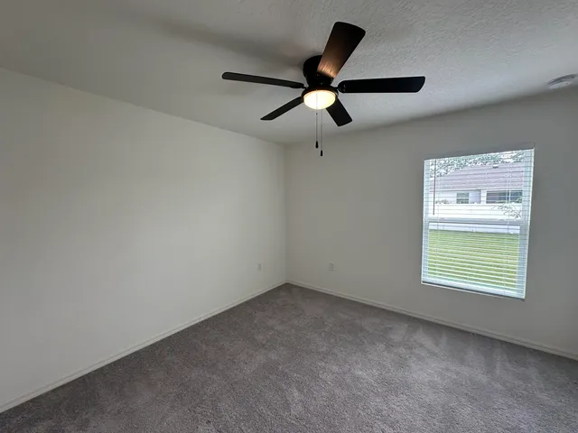 an empty room with a window and a fan