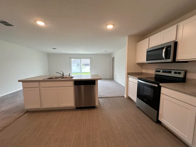 a kitchen with stainless steel appliances kitchen island granite countertop a stove a sink and a microwave