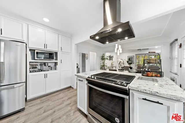 a kitchen with granite countertop stainless steel appliances a stove cabinets and wooden floor