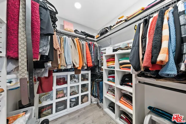a view of walk in closet with clothes and shoes