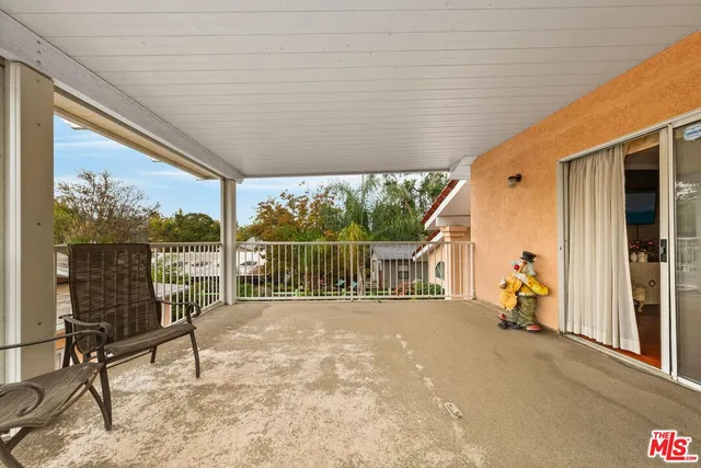 a view of a deck with wooden floor and roof with a garden