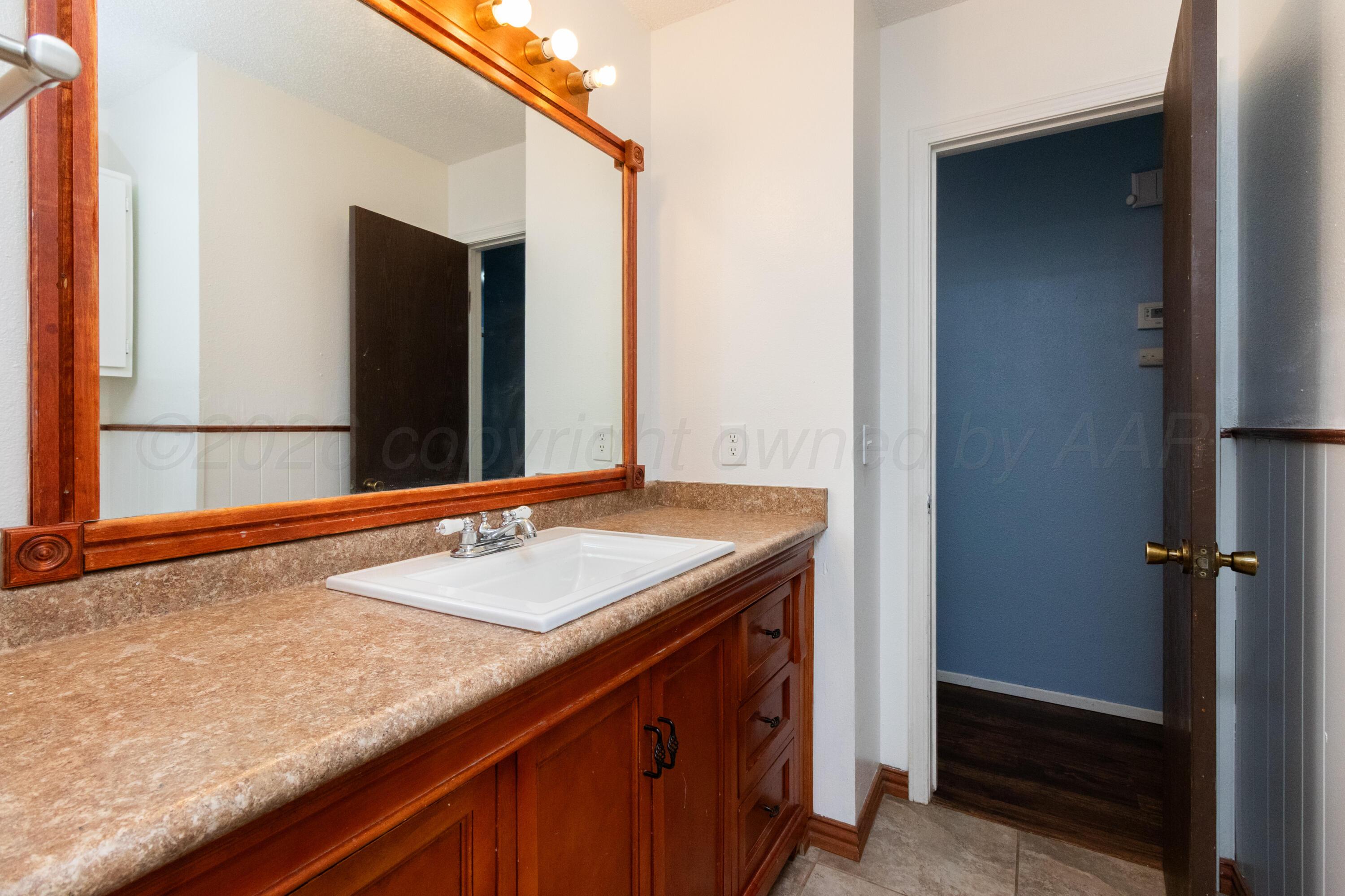 3211 Hodges Street Amarillo, TX 79103 - Photo 19 of 32 a bathroom with a granite countertop sink and a mirror