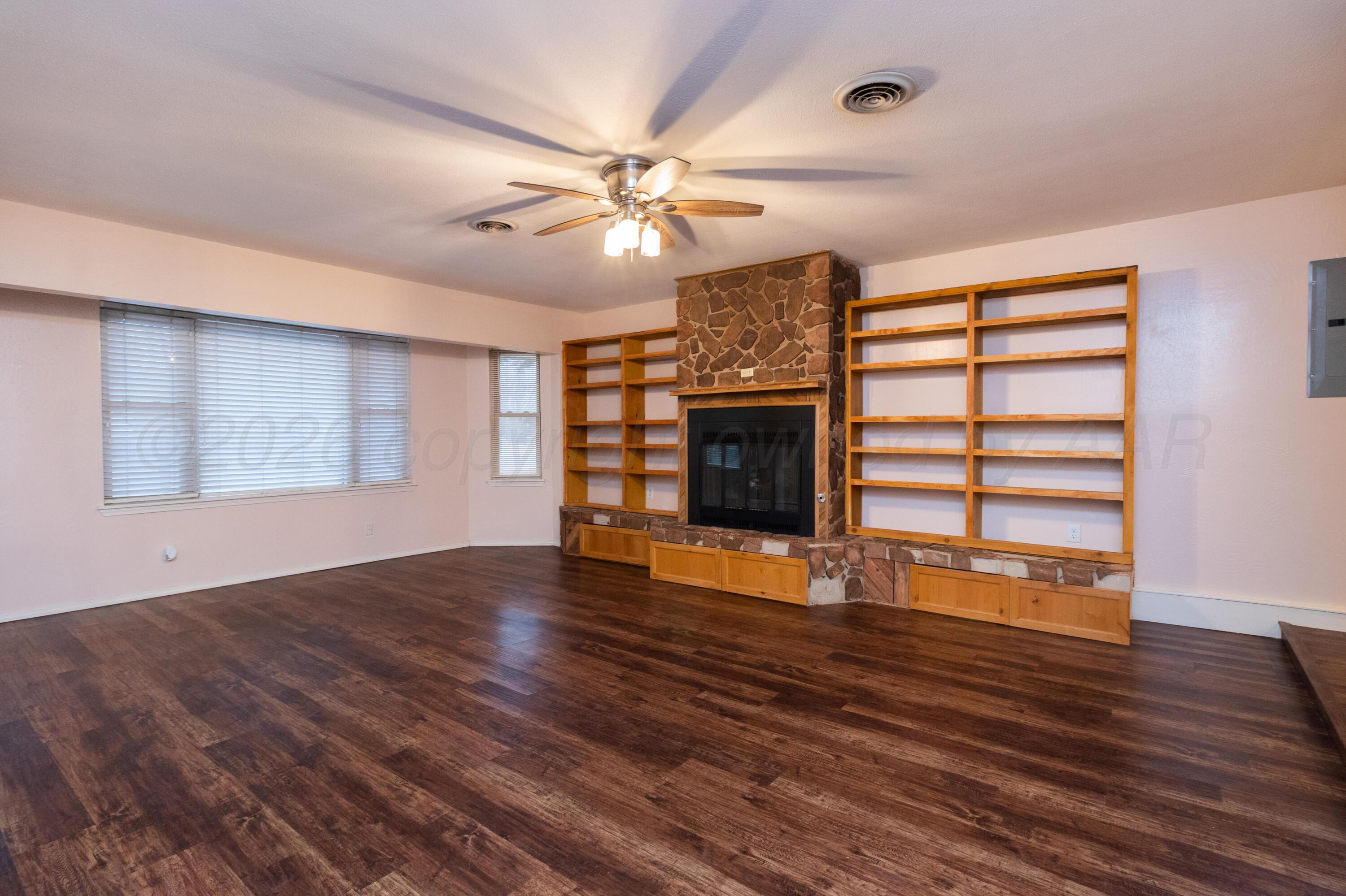 3211 Hodges Street Amarillo, TX 79103 - Photo 5 of 32 a view of an empty room with wooden floor fireplace and a window