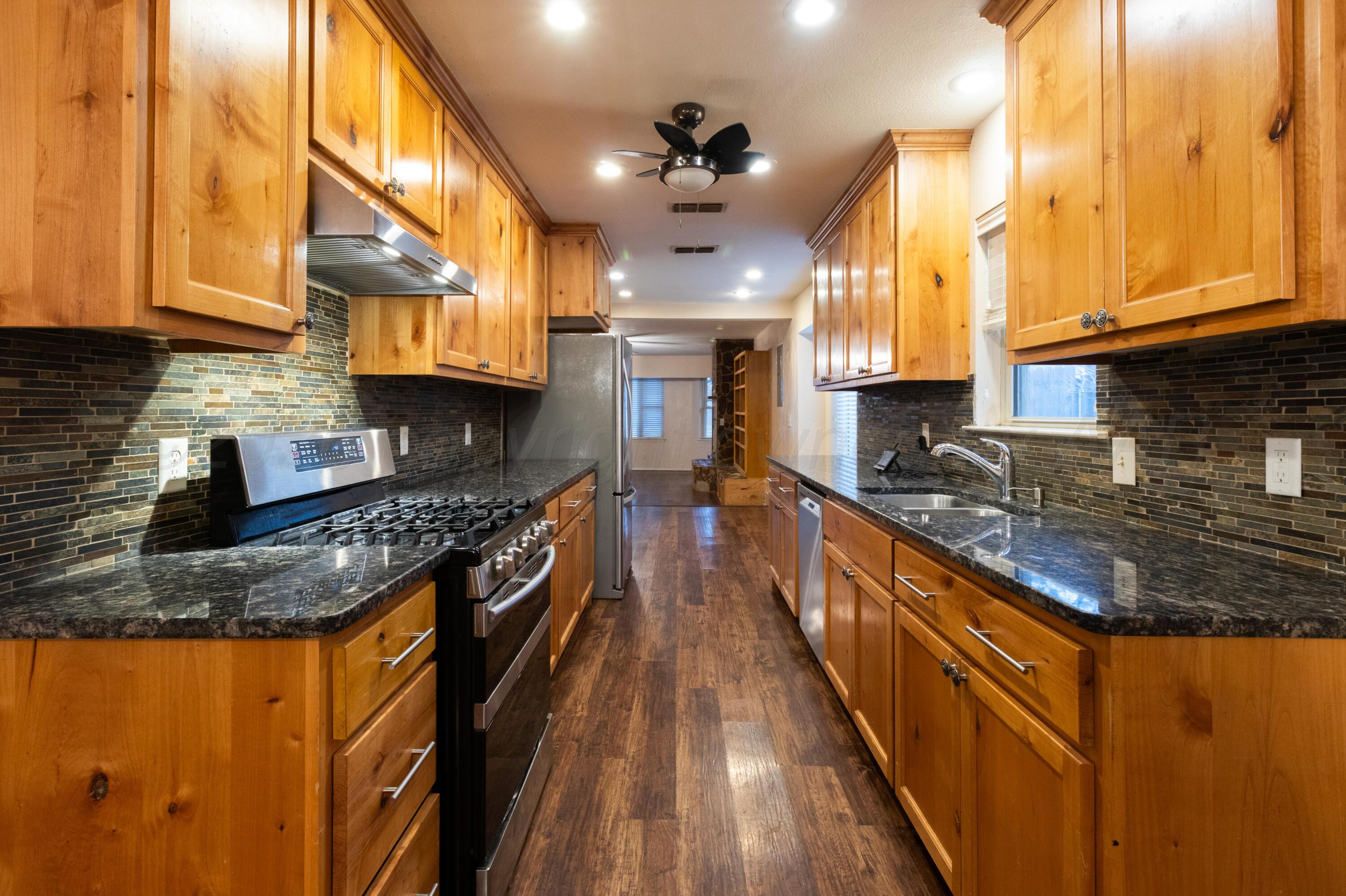 3211 Hodges Street Amarillo, TX 79103 - Photo 8 of 32 a kitchen with stainless steel appliances granite countertop wooden cabinets a stove a sink and dishwasher