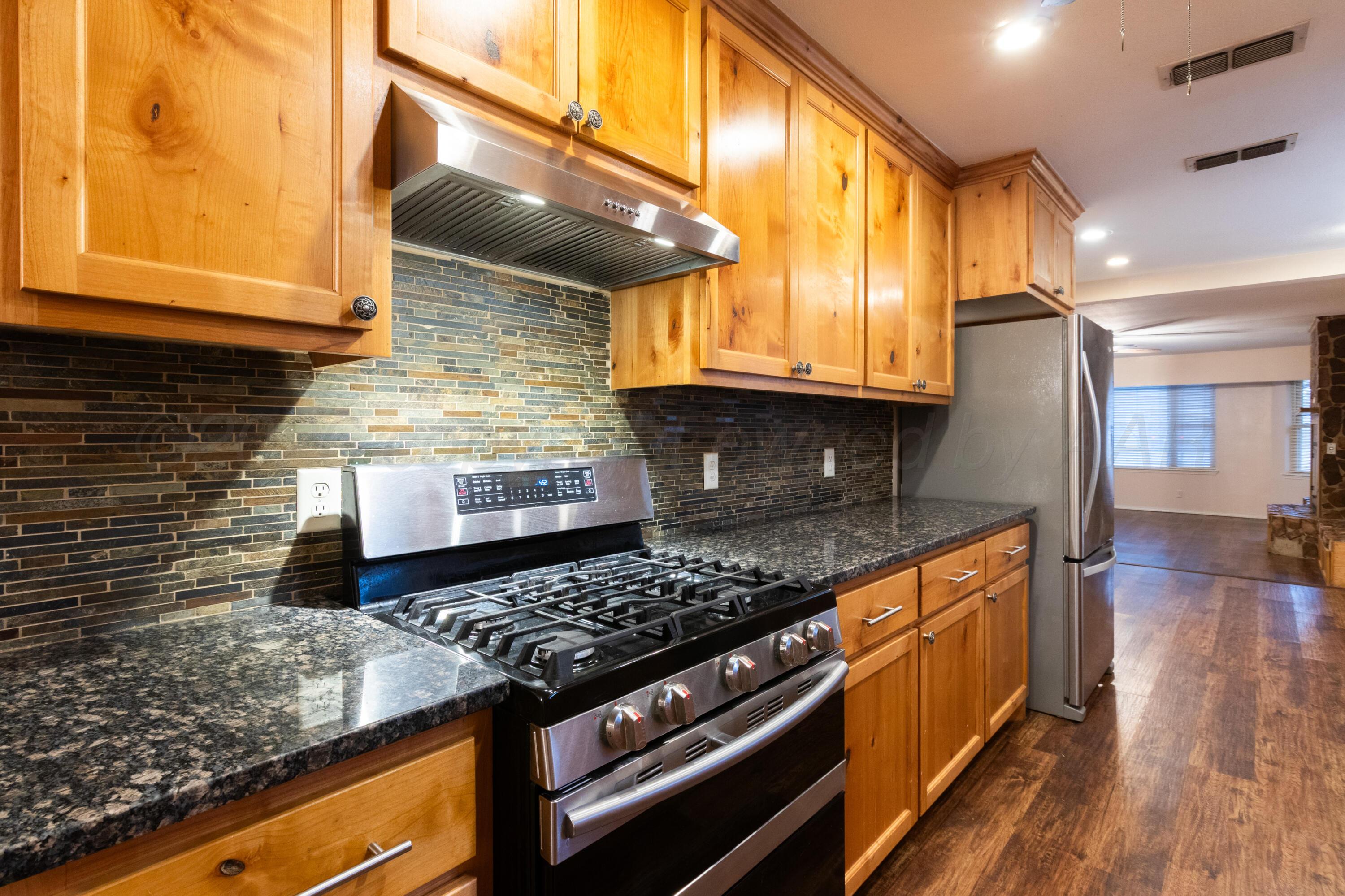 3211 Hodges Street Amarillo, TX 79103 - Photo 9 of 32 a kitchen with granite countertop wooden cabinets and stainless steel appliances