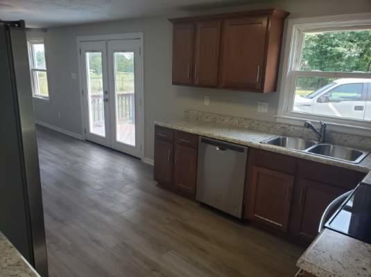 803 Mallard Point Road Wirtz, VA 24184 - Photo 9 of 10 a kitchen with granite countertop wooden cabinets a sink and dishwasher with wooden floor