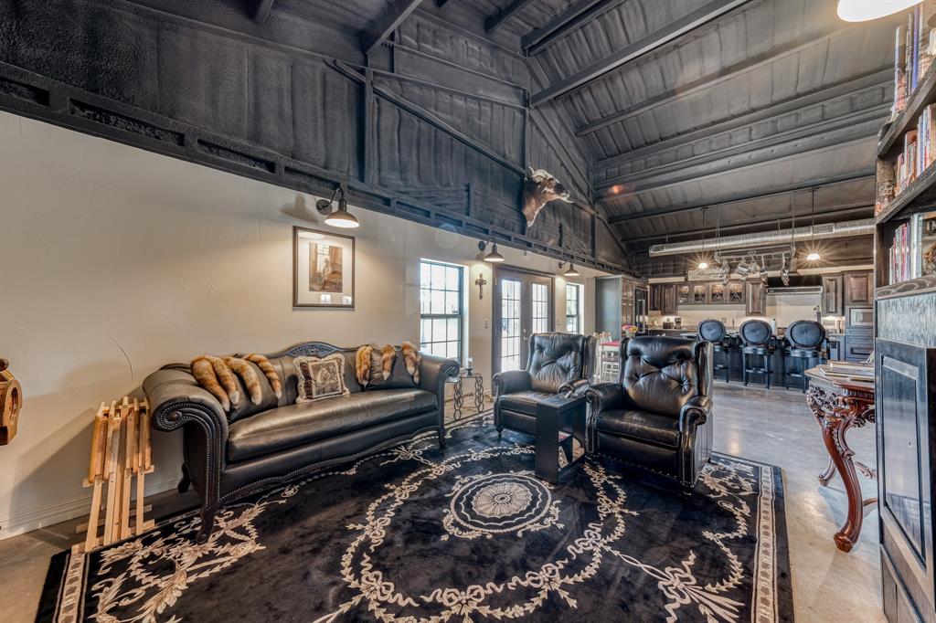 2337 Walsh Road Olney, TX 76374 - Photo 23 of 38 Vaulted wood-paneled ceiling with exposed beams, illuminated by wall-mounted sconces
