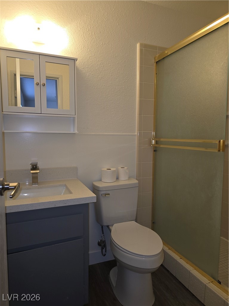 4219 Studio Street Las Vegas, NV 89115 - Photo 16 of 33 Bathroom featuring vanity, a shower stall, a textured wall, and dark wood-style flooring