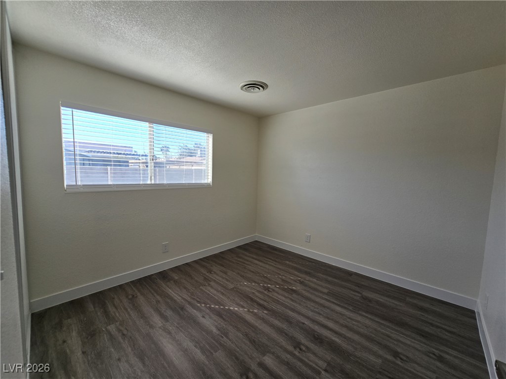 4219 Studio Street Las Vegas, NV 89115 - Photo 20 of 33 Empty room with a textured ceiling and dark wood-style flooring