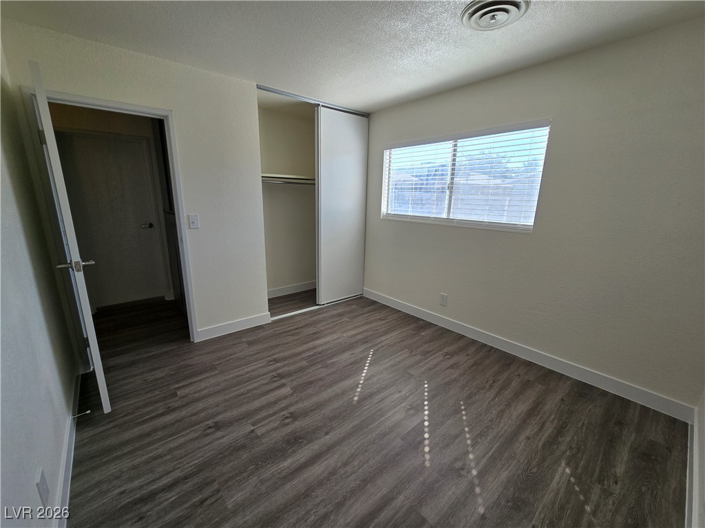 4219 Studio Street Las Vegas, NV 89115 - Photo 21 of 33 Unfurnished bedroom featuring dark wood-style floors, a textured ceiling, and a closet