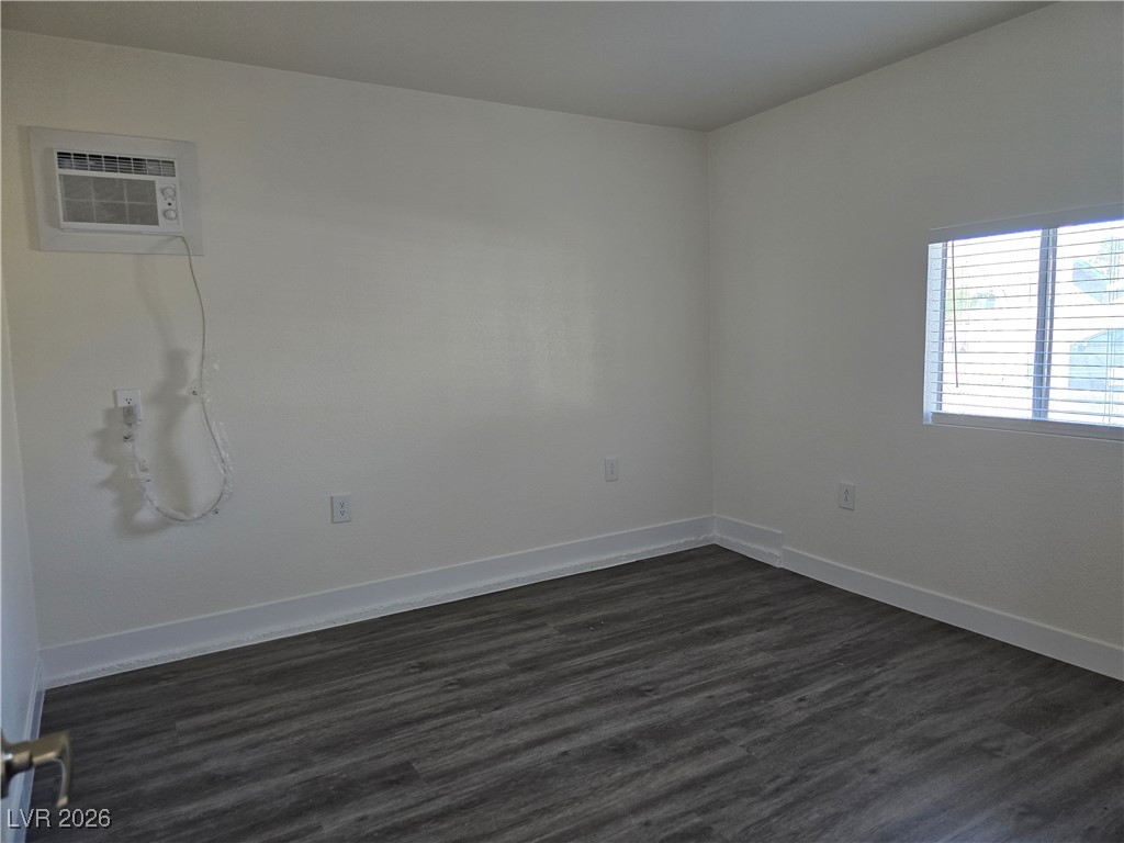4219 Studio Street Las Vegas, NV 89115 - Photo 5 of 33 Empty room with dark wood-style floors and a wall mounted AC