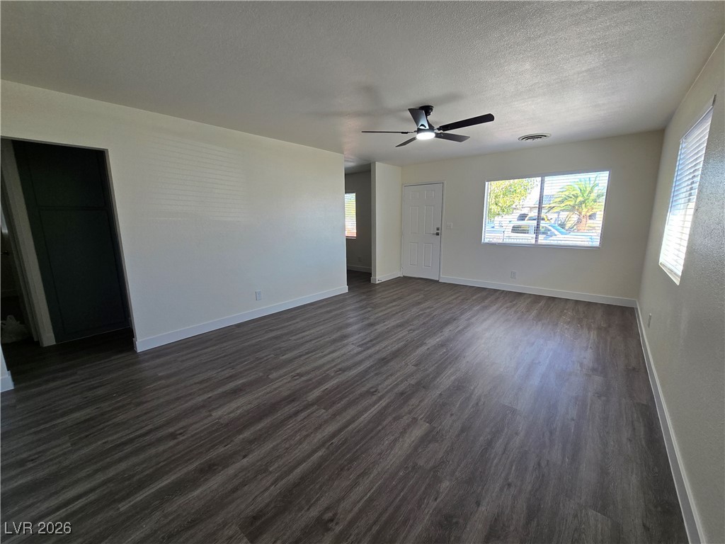 4219 Studio Street Las Vegas, NV 89115 - Photo 8 of 33 Unfurnished living room with dark wood-style flooring, plenty of natural light, a textured ceiling, and a ceiling fan