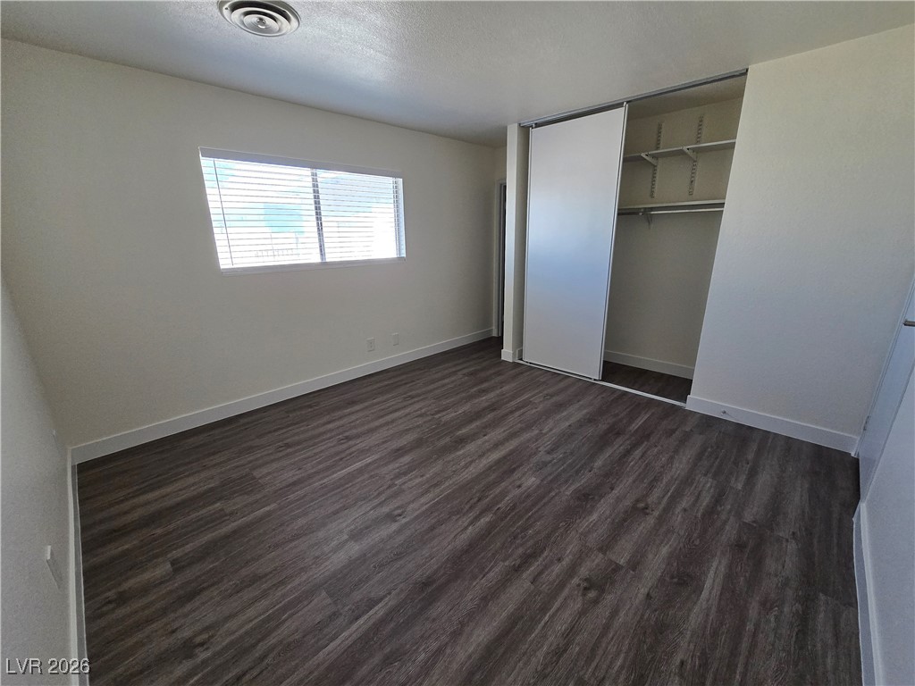 4219 Studio Street Las Vegas, NV 89115 - Photo 10 of 33 Unfurnished bedroom with dark wood-style flooring, a closet, and a textured ceiling