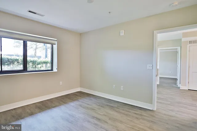 a view of an empty room with wooden floor and a window