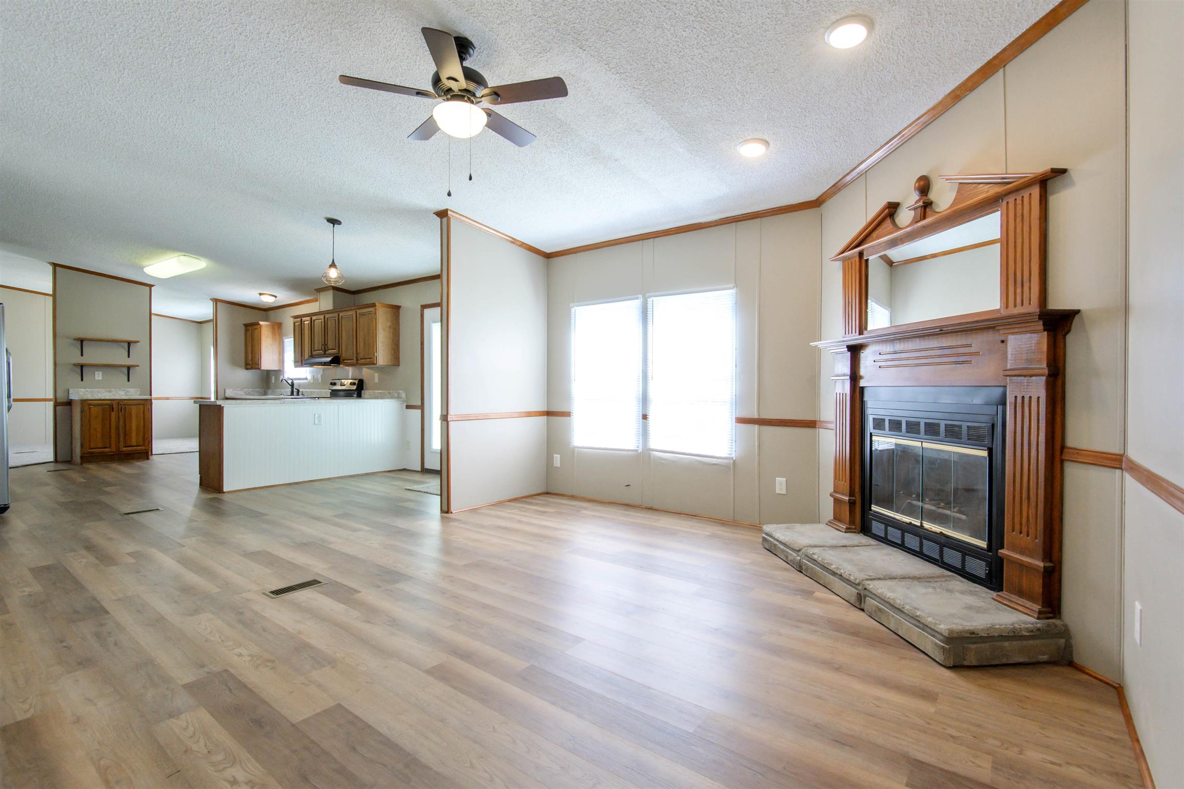 4489 Goodman Road Adams, TN 37010 - Photo 7 of 30 a view of a kitchen with a stove cabinets wooden floor and a ceiling fan