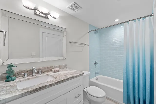 a bathroom with a granite countertop sink a toilet and shower