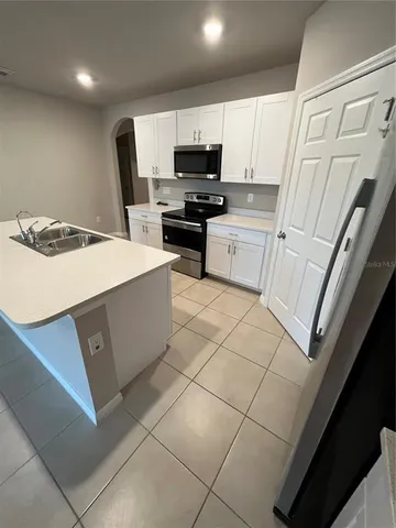 a kitchen with a sink a stove top oven and cabinetry
