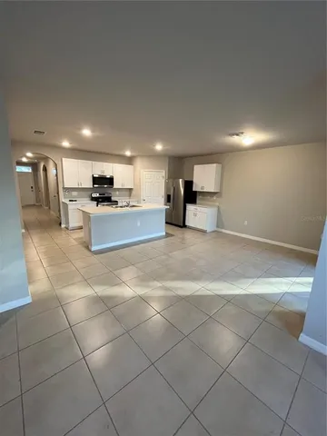 a large kitchen with kitchen island a stove a sink a counter top space and cabinets