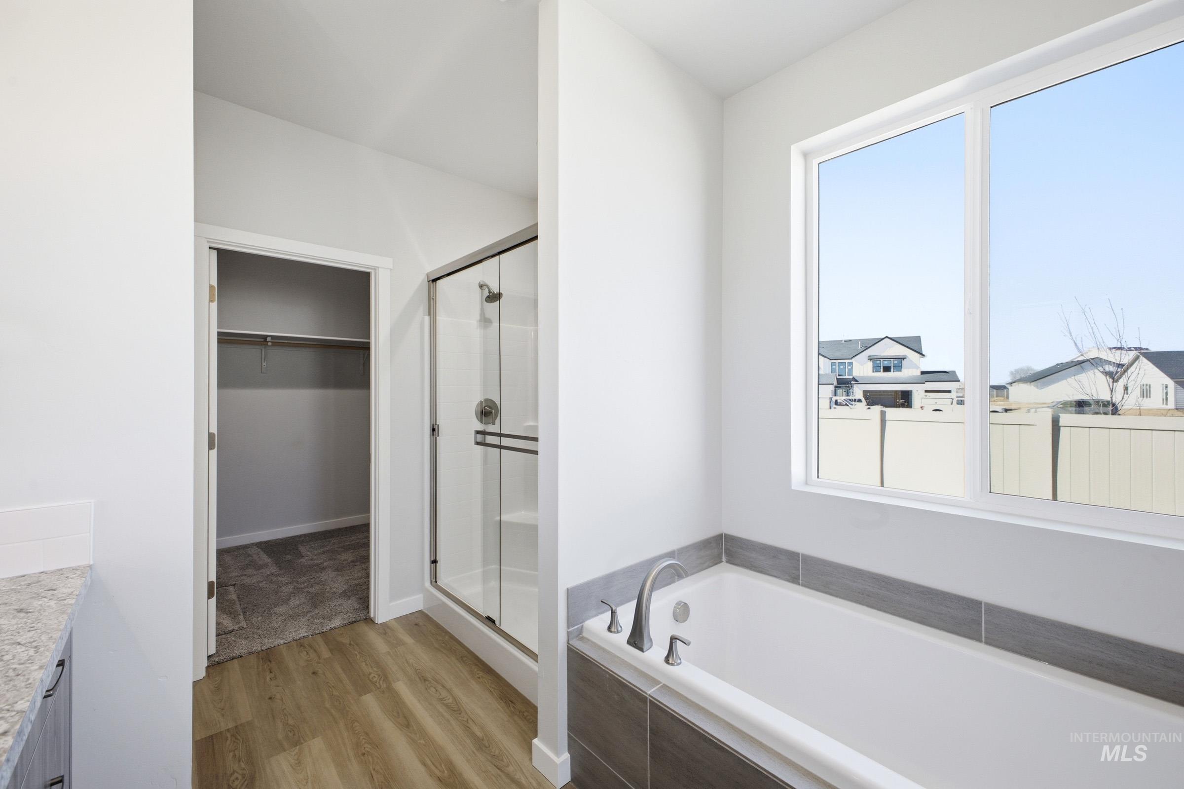 13633 Redway Court Caldwell, ID 83607 - Photo 26 of 29 Full bathroom featuring a bath, vanity, light wood-style flooring, a shower stall, and a walk in closet