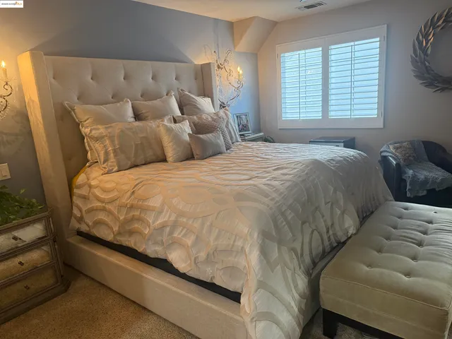 a large bed sitting in a bedroom next to a window