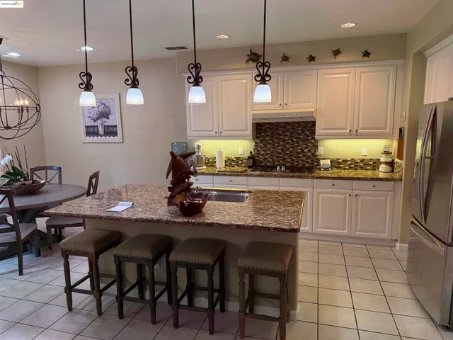 a kitchen with stainless steel appliances granite countertop a sink a stove a refrigerator and island with wooden floor