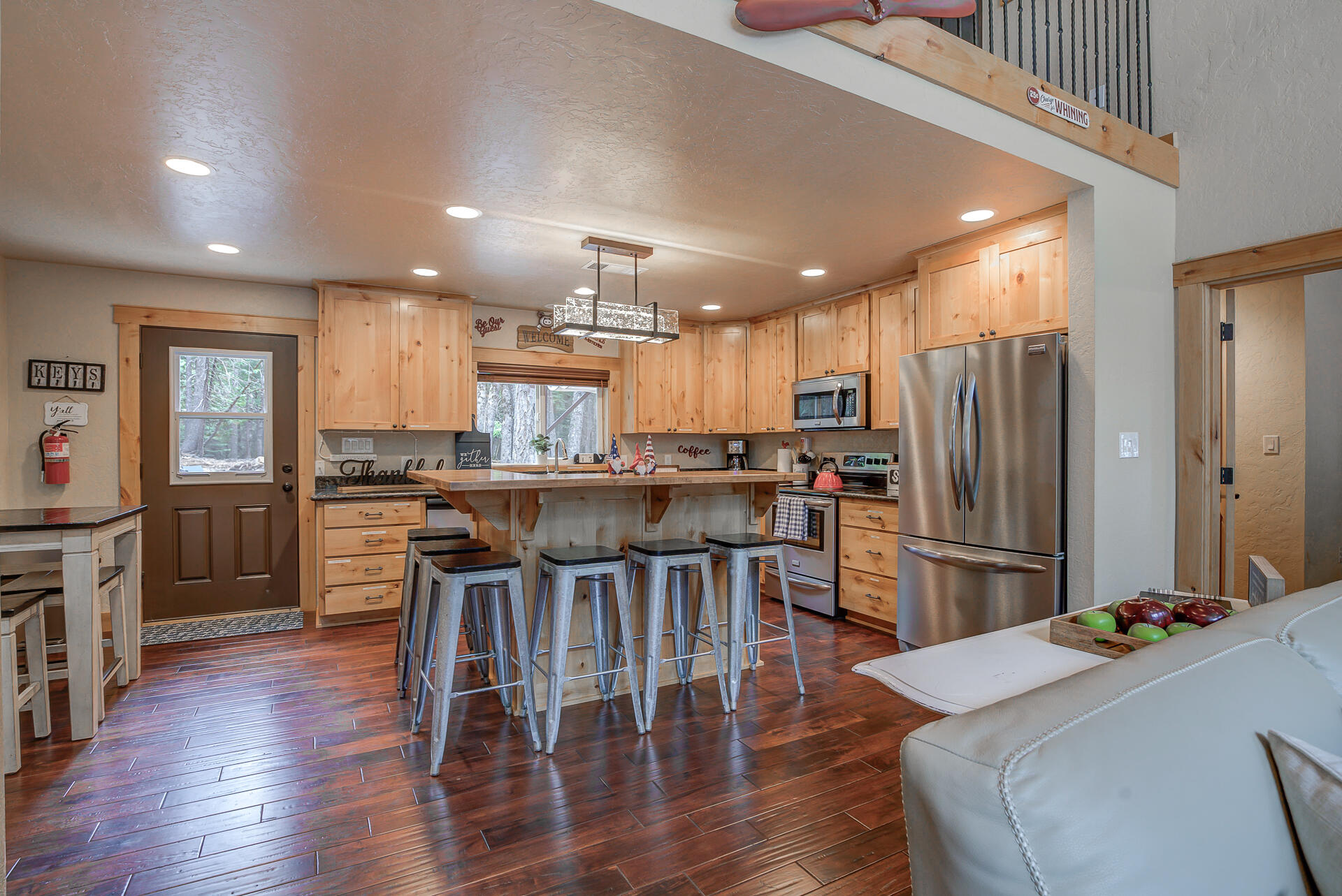34607 Mountain Haven Road Shingletown, CA 96088 - Photo 10 of 63 a kitchen with stainless steel appliances kitchen island granite countertop a refrigerator a stove a sink a dining table and chairs with wooden floor
