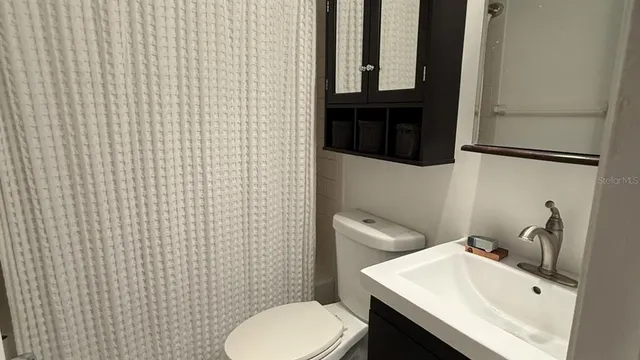 a bathroom with a sink a toilet and shower curtain