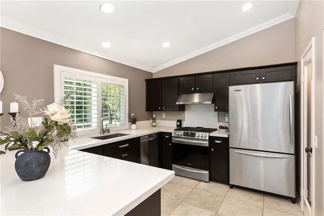 a kitchen with stainless steel appliances a sink a stove a refrigerator a center island and a window