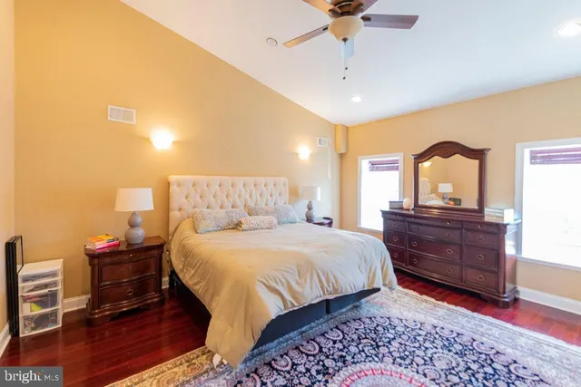 a bedroom with a bed and a dresser with wooden floor
