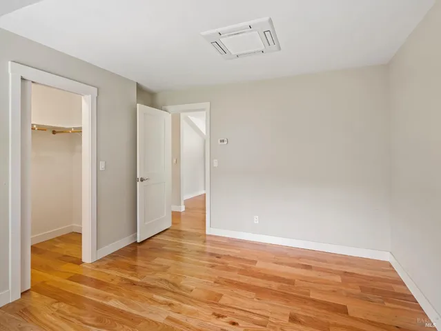 a view of an empty room with wooden floor and closet