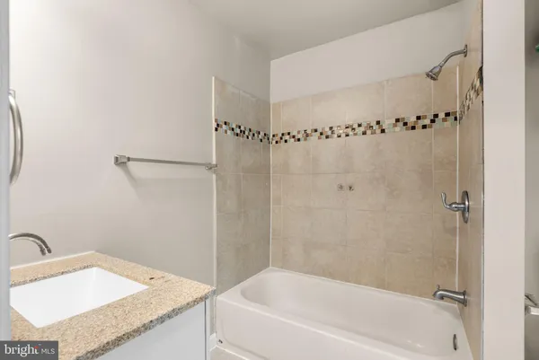 a bathroom with a granite countertop sink a mirror and a bathtub