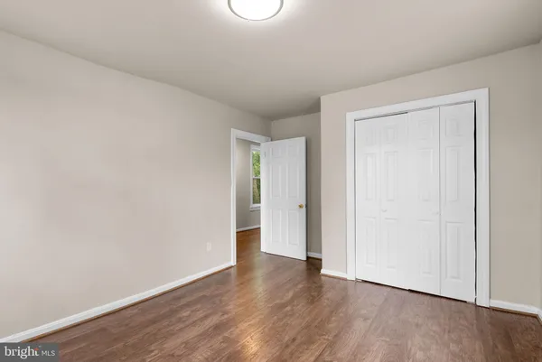 a view of an empty room with wooden floor and closet