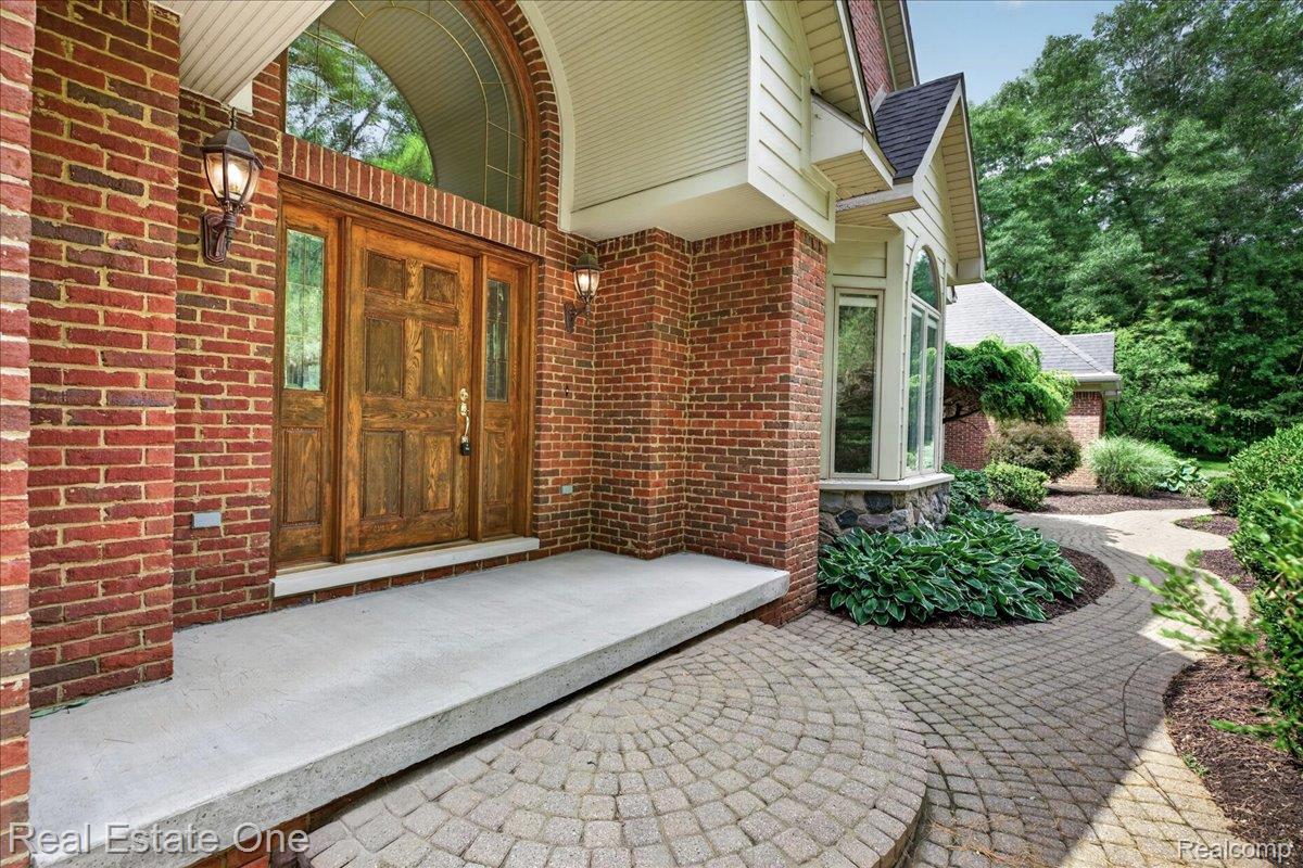 425 Courtney Road Leonard, MI 48367 - Photo 5 of 89 Brick exterior featuring a wooden double-door entry with sidelights and an arched transom window