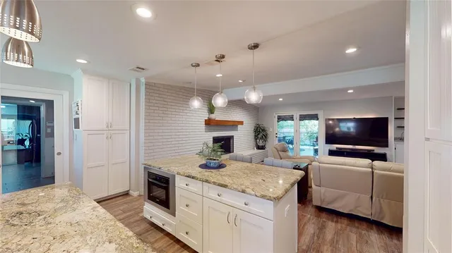 a living room with stainless steel appliances kitchen island granite countertop furniture and a flat screen tv