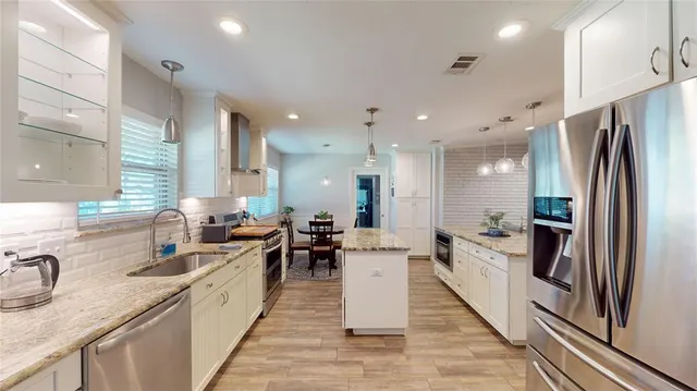 a large kitchen with stainless steel appliances a sink a stove and a refrigerator