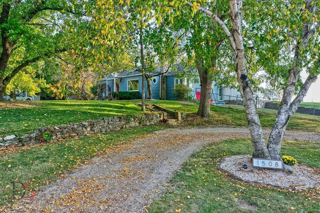 a front view of a house with a yard and trees