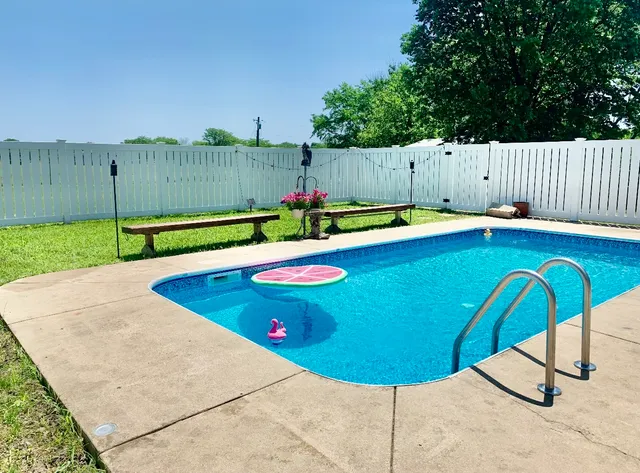 a view of a backyard with swimming pool and furniture