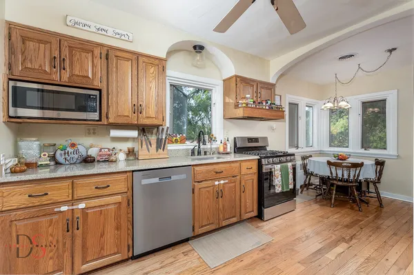 a kitchen with stainless steel appliances granite countertop a stove a sink dishwasher and microwave with wooden cabinets