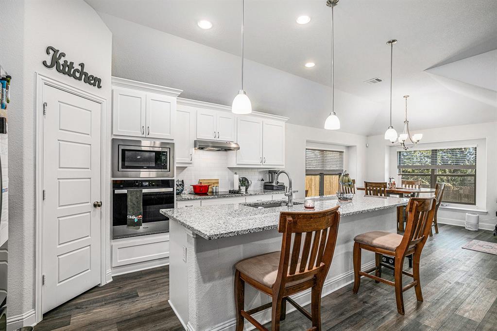 417 Elyse Road Keene, TX 76059 - Photo 4 of 17 a kitchen with stainless steel appliances granite countertop a kitchen island hardwood floor sink stove dining table and chairs