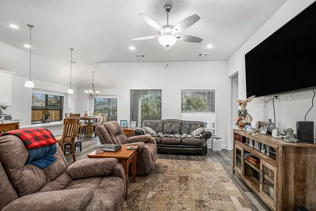 a living room with furniture a flat screen tv and a chandelier