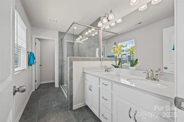 a spacious bathroom with a double vanity sink a mirror a shower and a window