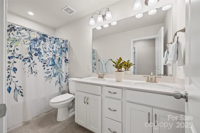 a bathroom with a double vanity sink mirror and toilet