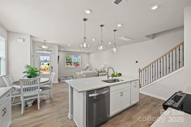 a kitchen with stainless steel appliances kitchen island a white table chairs and a potted plant