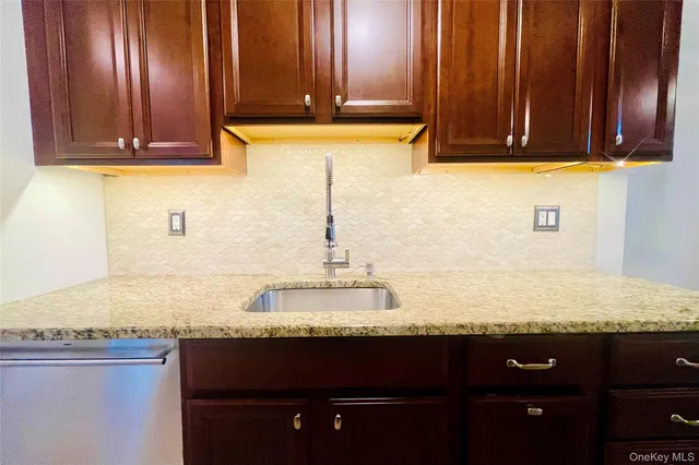 a bathroom with granite countertop a sink and a wooden cabinets