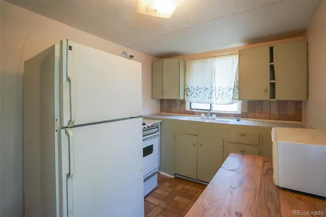 a kitchen with granite countertop a refrigerator a sink a stove a washer and dryer