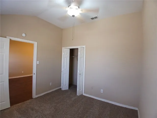 an empty room with closet and a chandelier fan