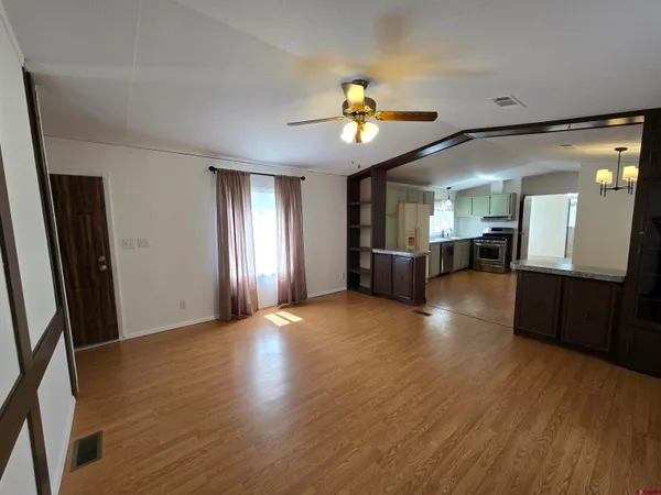 an empty room with wooden floor and natural light