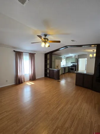 a view of an empty room with window and wooden floor