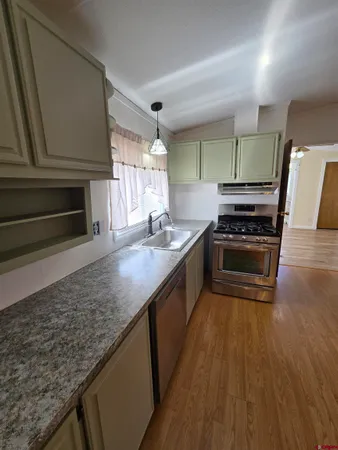 a kitchen with stainless steel appliances granite countertop a stove a sink and a microwave