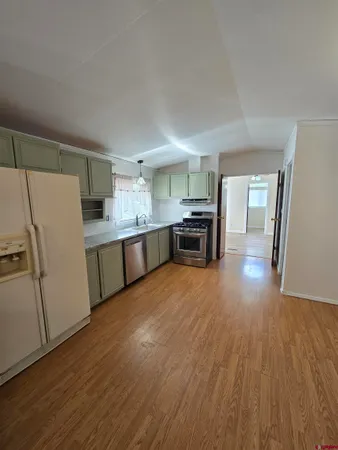 a large kitchen with a wooden floor and a refrigerator